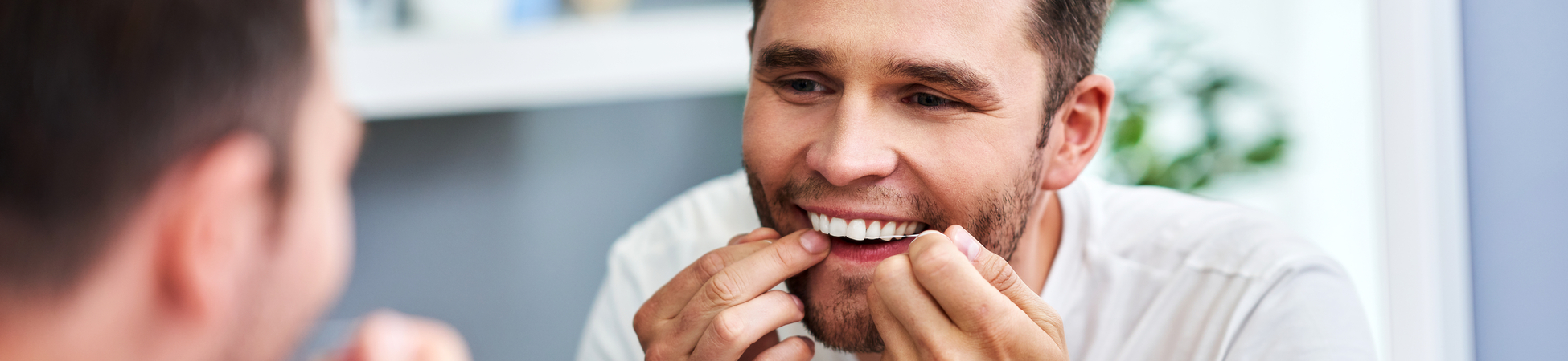 man looking in the mirror to floss